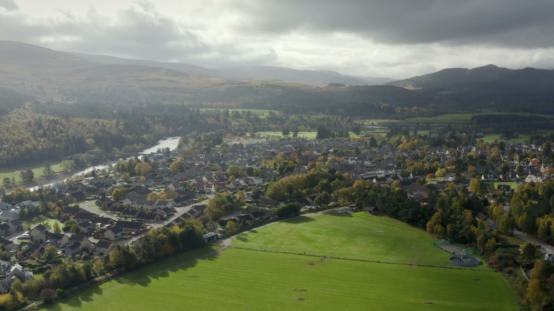 Ballater from the air, the River Dee curving past the town, the hills of Deeside under heavy cloud.
