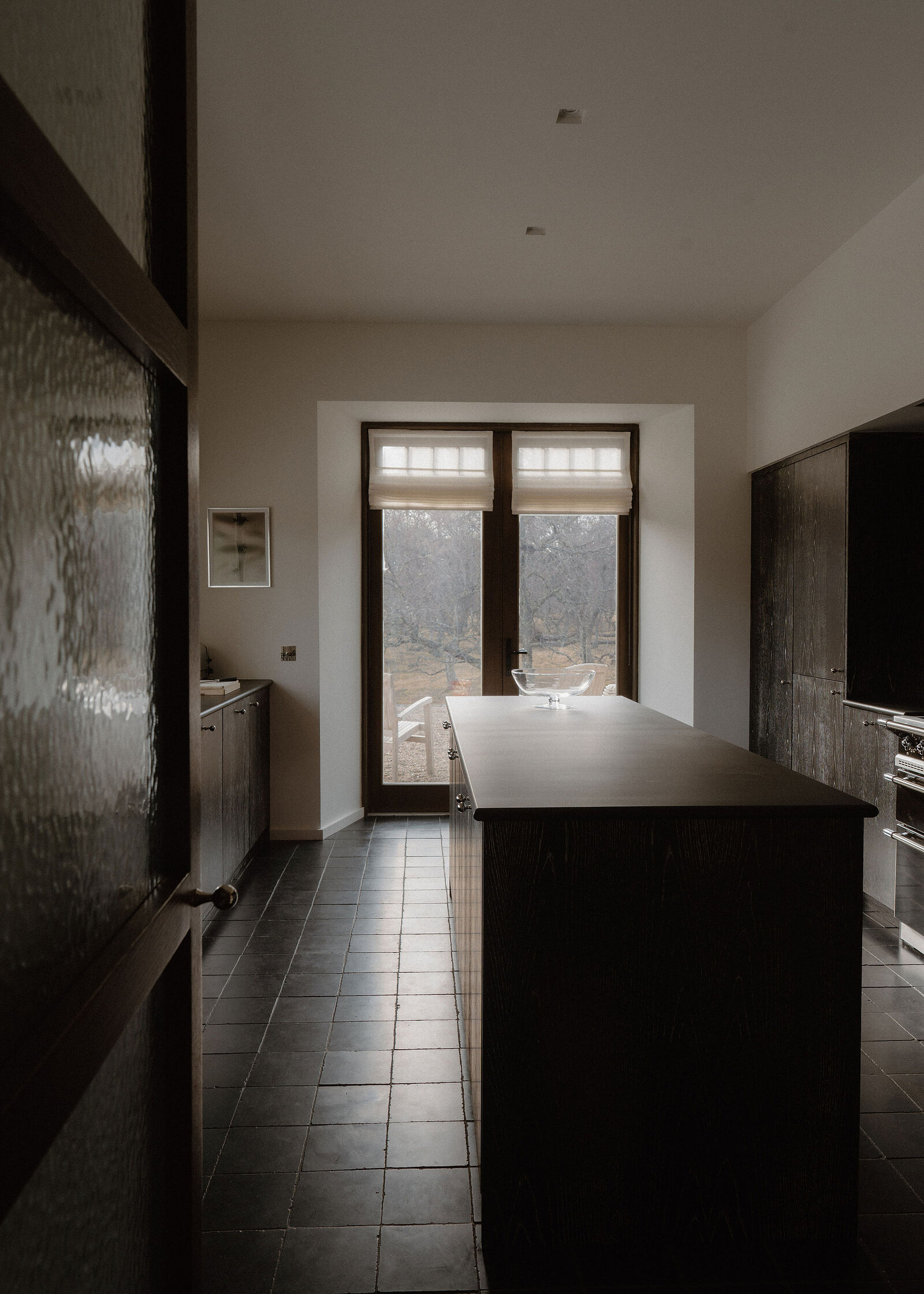 Down the length of the kitchen: the long dark island, a range cooker and the French windows at the end.