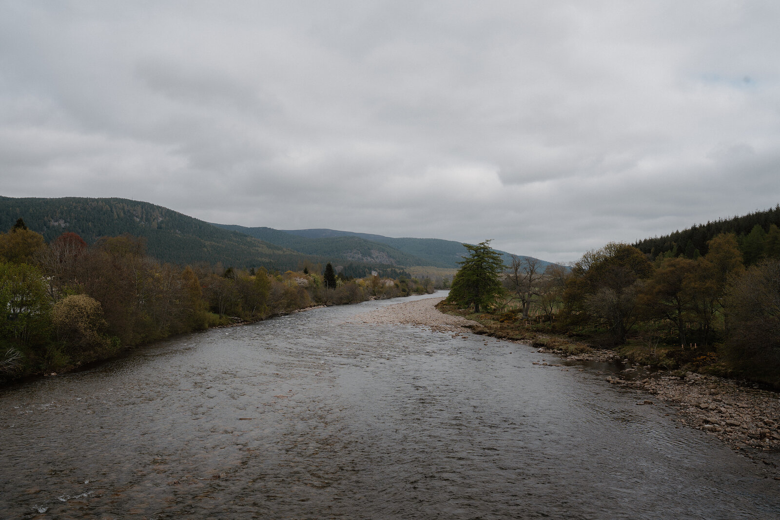 The River Dee flows through a wooded valley near Ballater, hills rising on either bank