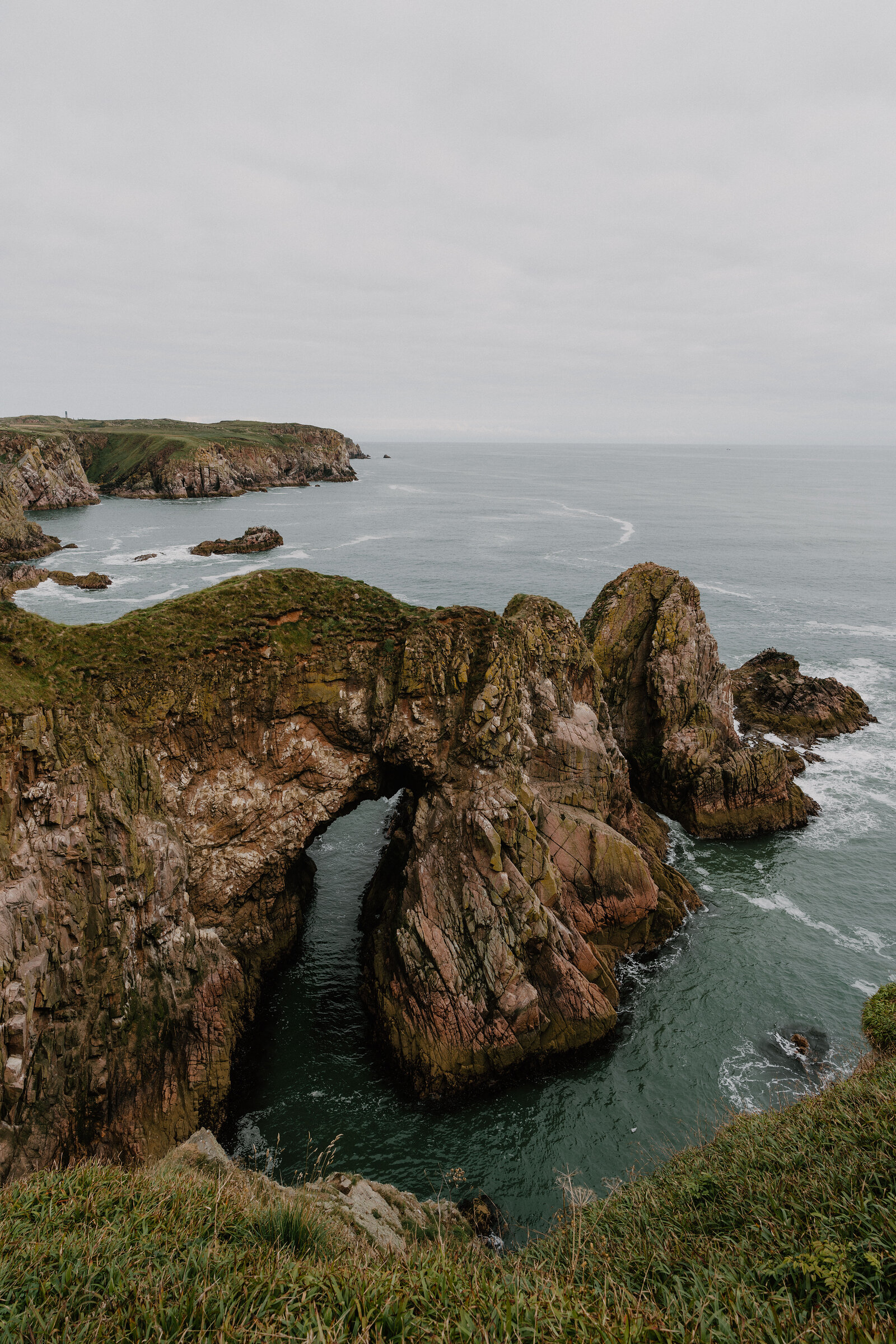 A natural rock arch spanning a narrow inlet, waves washing beneath it