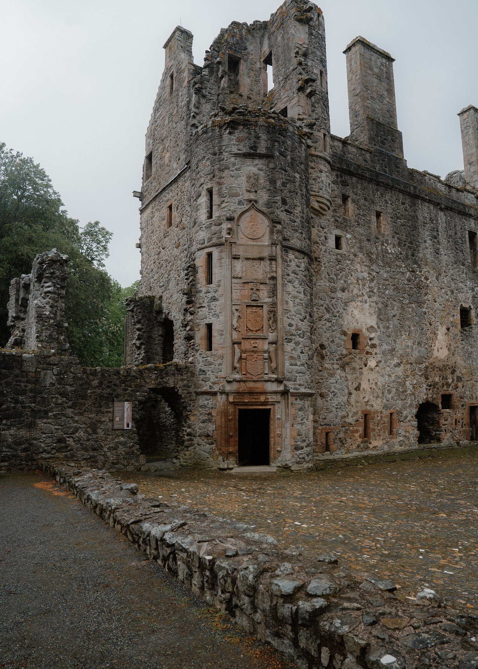 The ruined facade of Huntly Castle, its doorway framed by a heavily carved heraldic panel