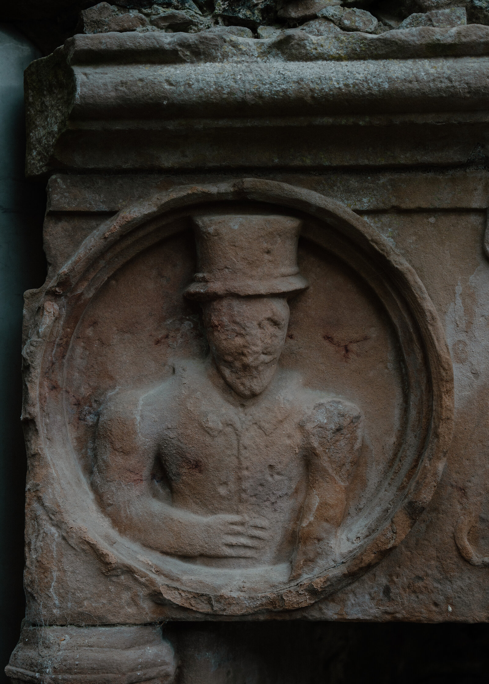A carved stone roundel at Huntly Castle depicting a top-hatted figure in relief