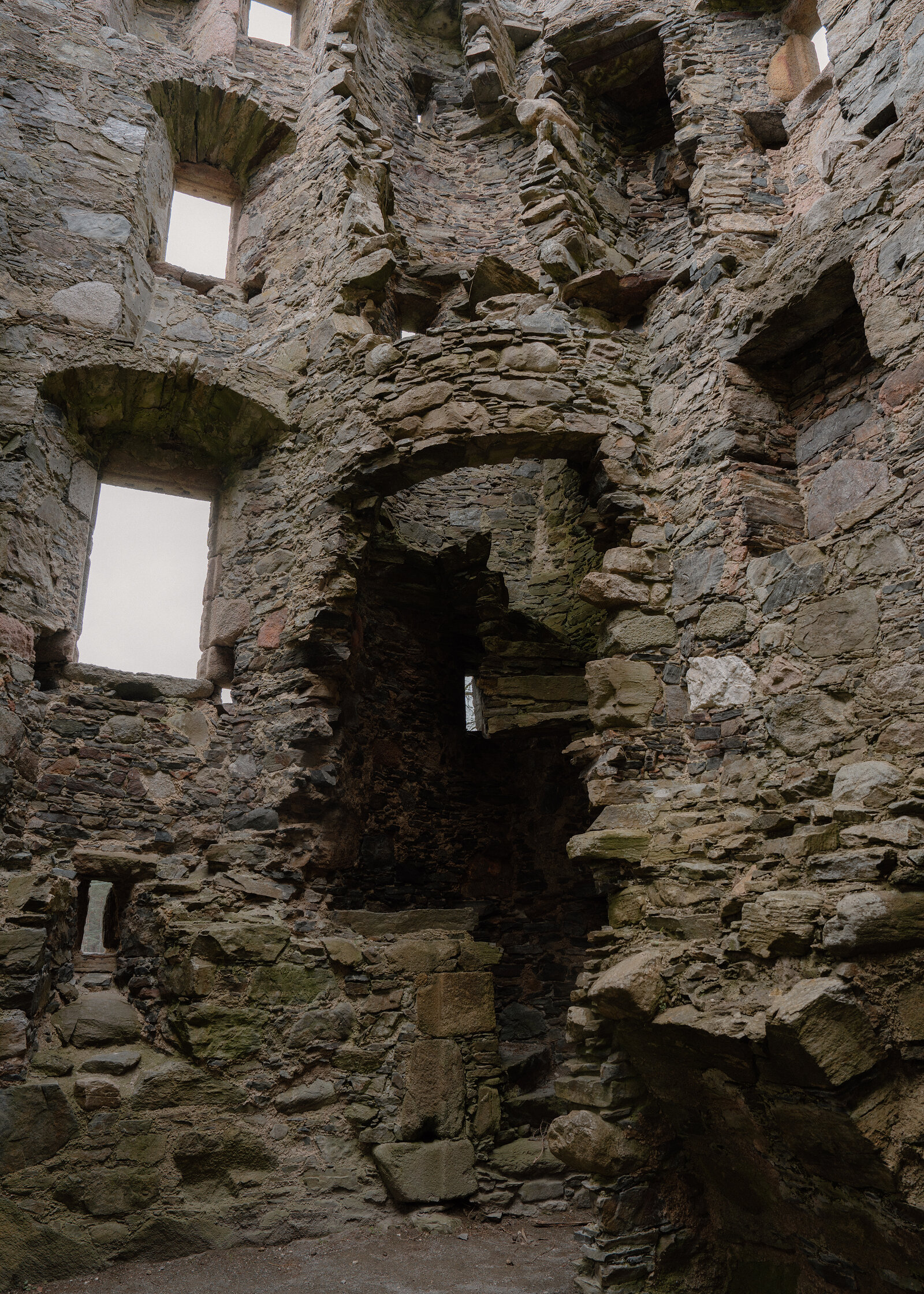 A jagged breach opens through the stone wall inside Knock Castle's ruined tower