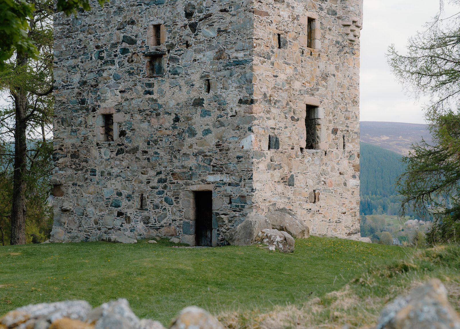 The stone tower of Knock Castle with a doorway open onto a grassy clearing