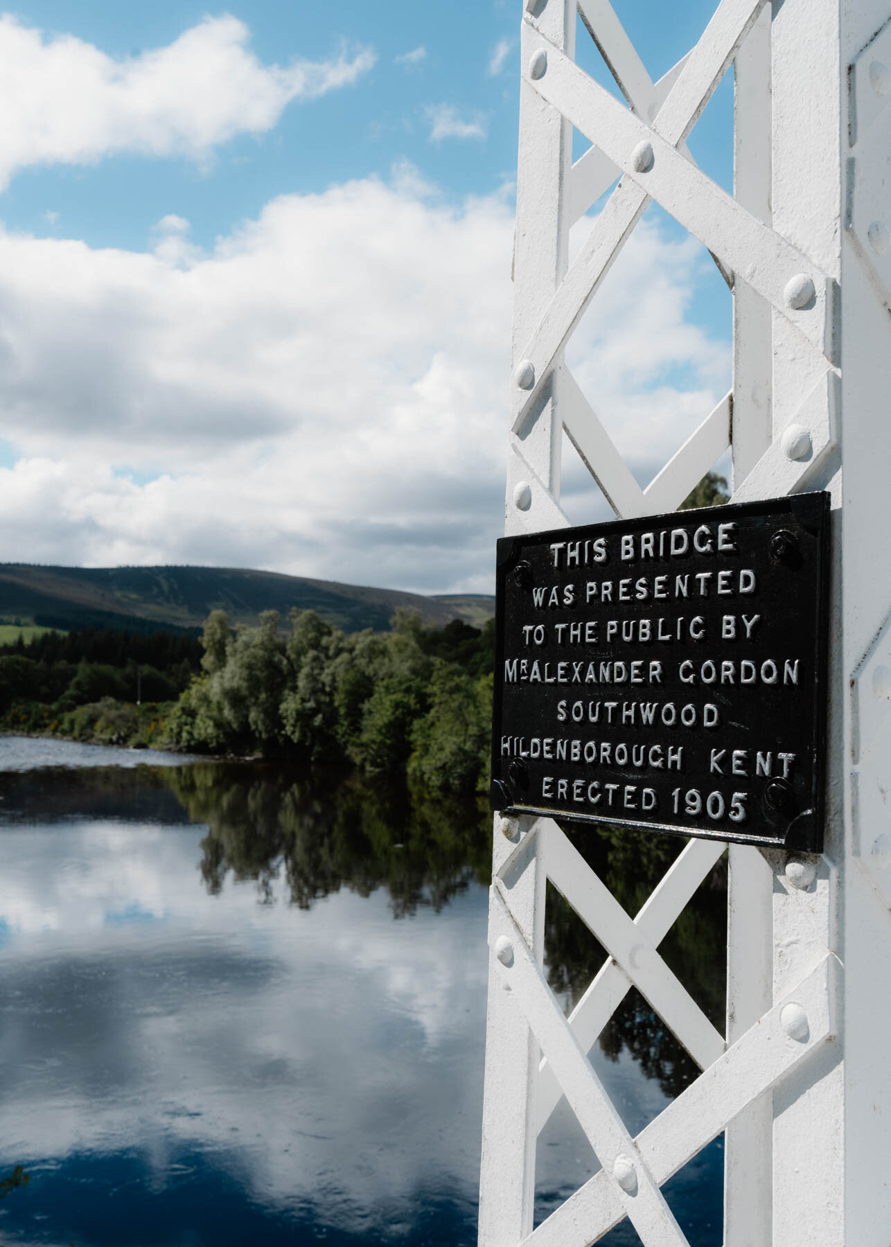 A plaque reading This bridge was presented to the public by Mr Alexander Gordon Southwood, mounted on a white lattice tower