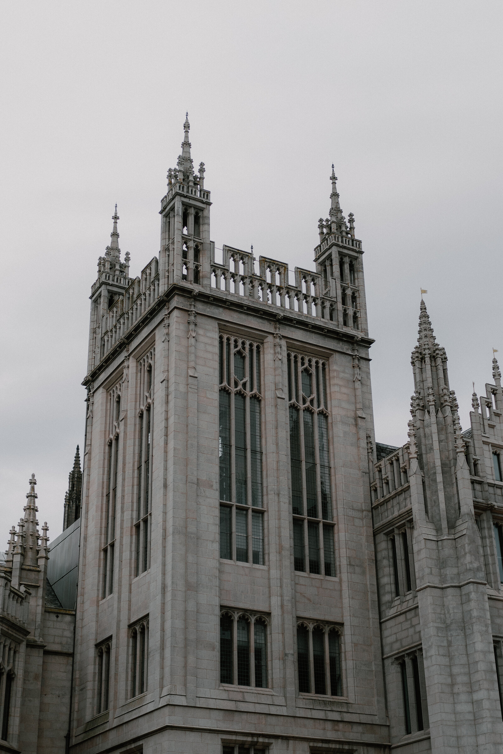 A Gothic granite tower rises with clustered pinnacles against a cloudy sky.