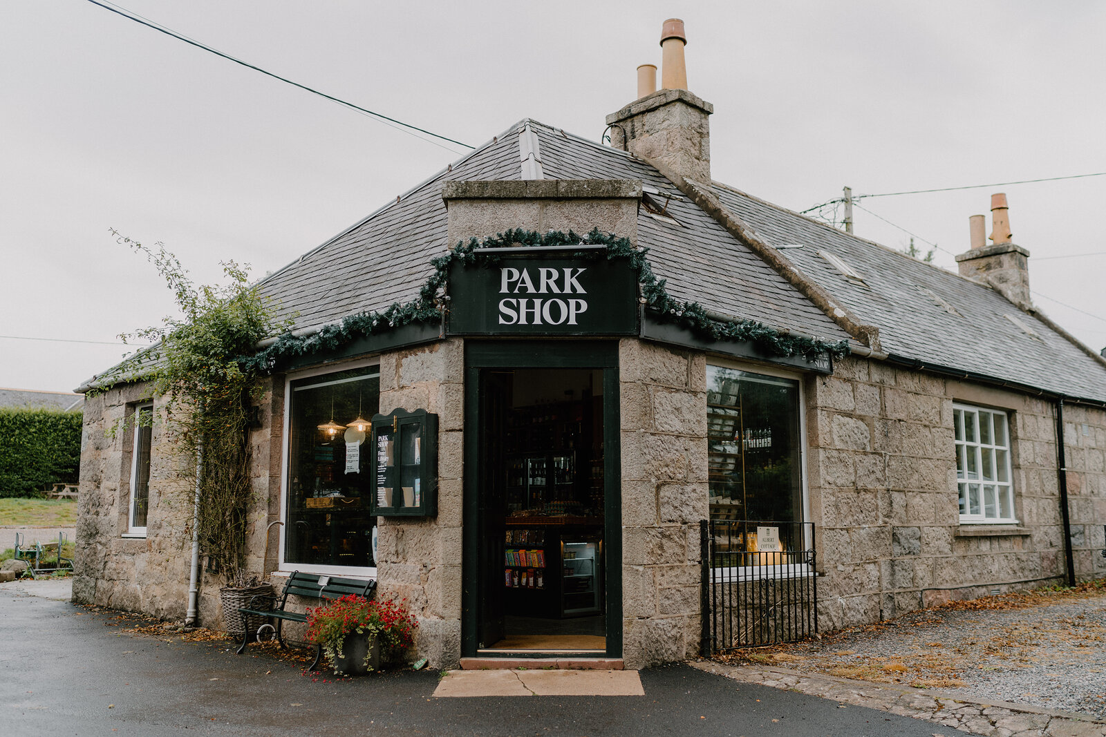 The Park Shop's granite frontage in Aberdeenshire, its green awning and hanging garland framing the doorway.