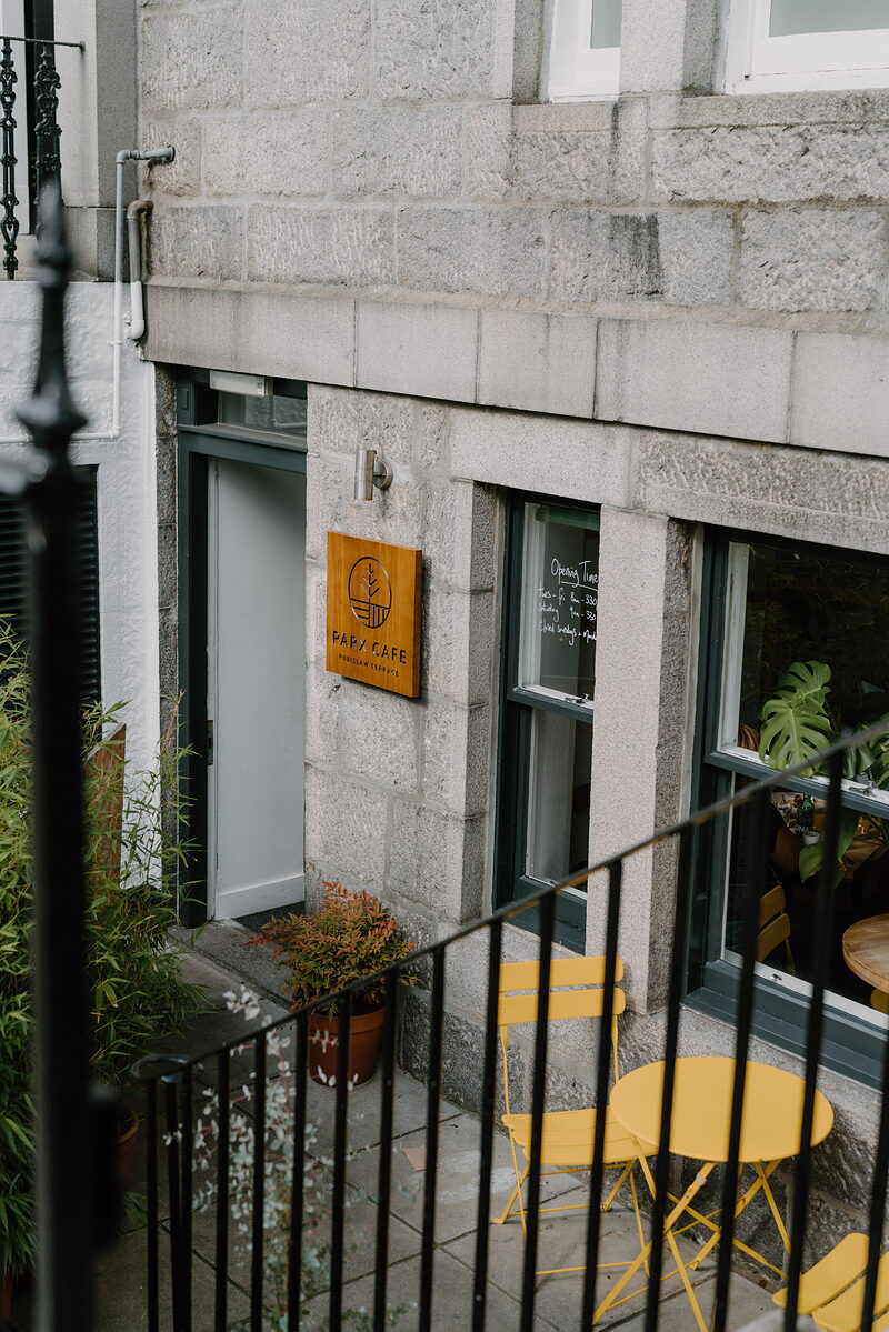 The Park Cafe's granite frontage in Aberdeenshire, yellow bistro tables set out behind its railings.