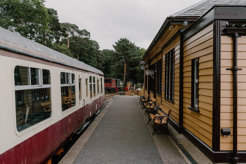 A heritage railway platform in Aberdeenshire, benches lining a cream-and-red station building beside the waiting train.