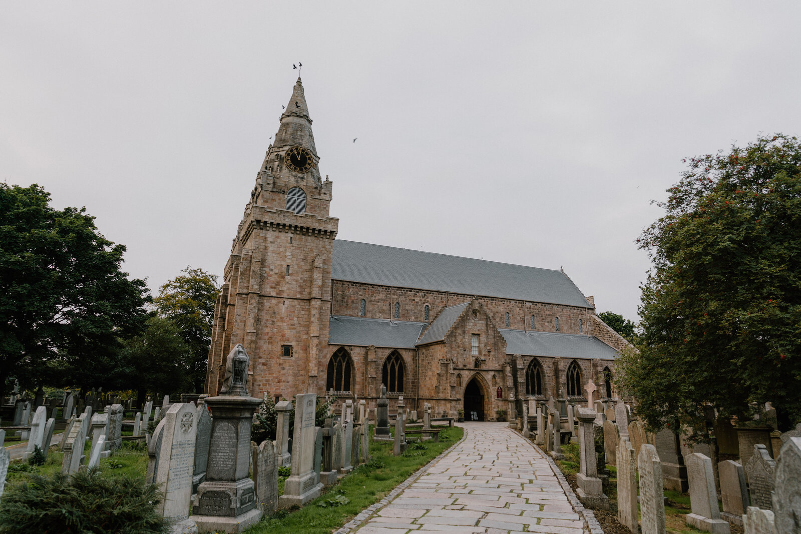 A church with a clock tower rising above its graveyard in Aberdeenshire.