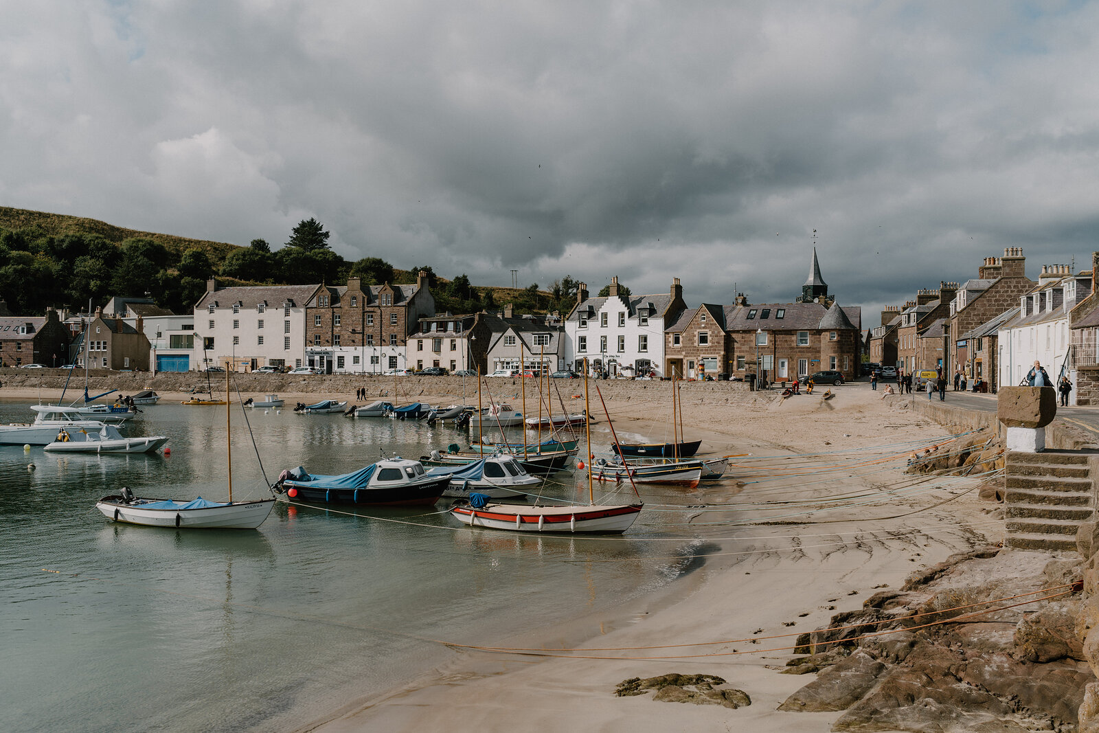 A fishing harbour village in Aberdeenshire, small boats moored before colourful waterfront buildings.