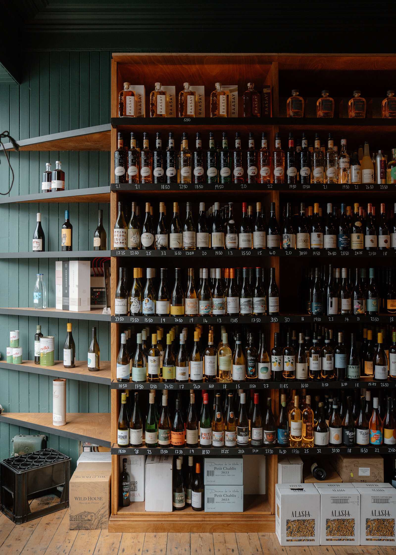Shelves of wine and spirit bottles lined against a dark green panelled wall