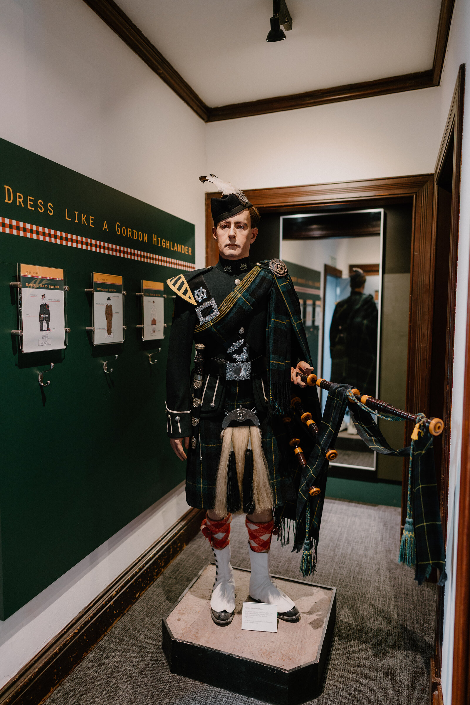A mannequin in full Gordon Highlander dress uniform stands beside a wall inviting visitors to dress like a Gordon Highlander.