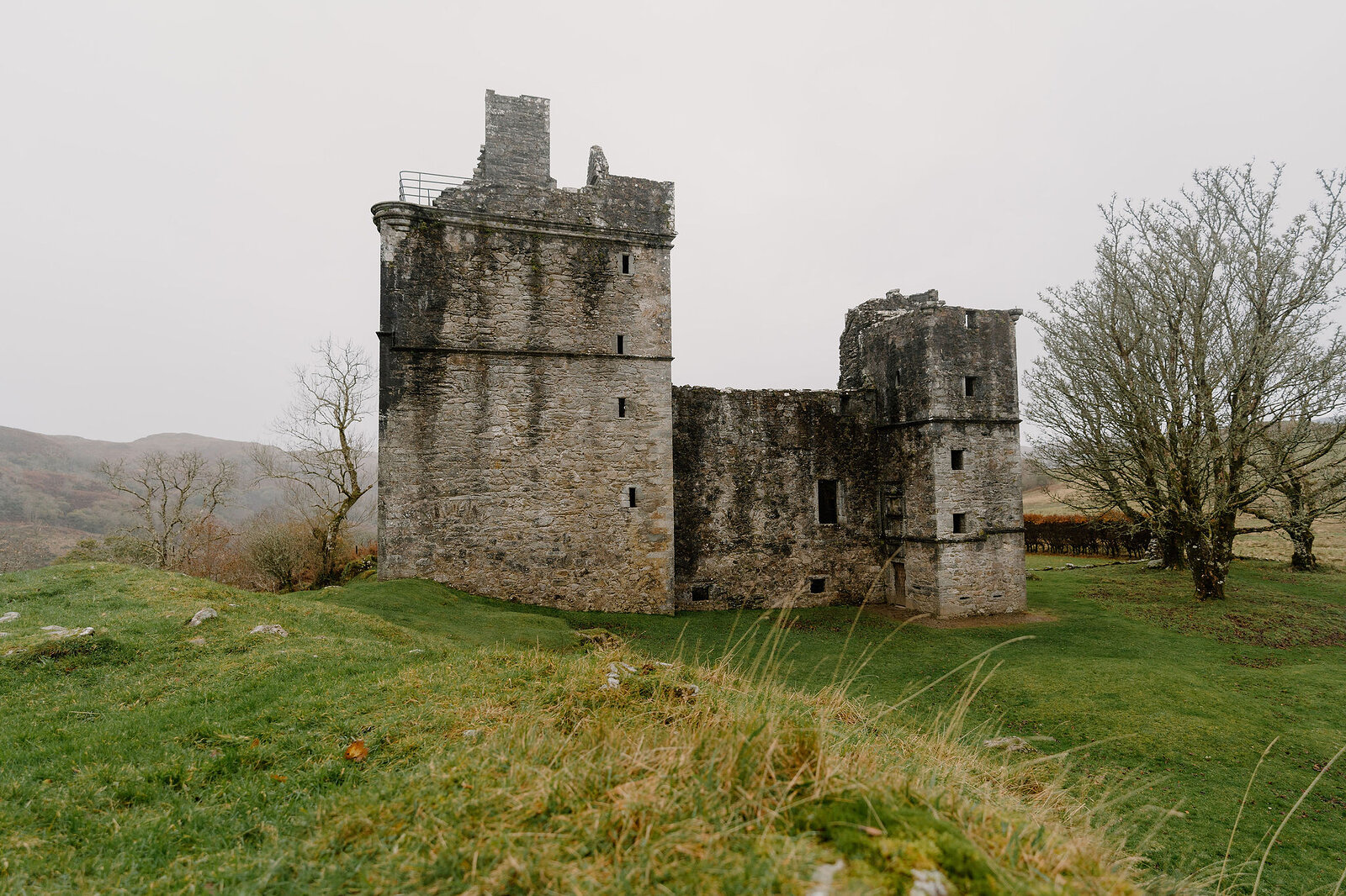 A ruined stone tower keep with a stepped gable, connected by a lower wing to a second tower