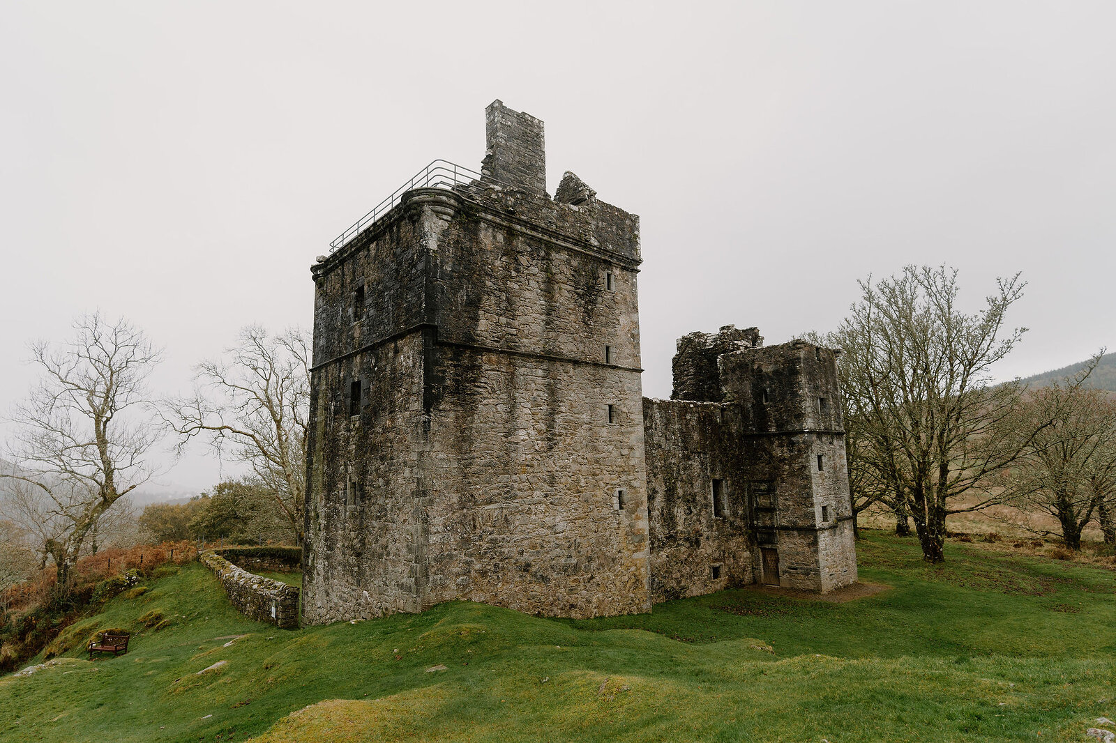 A ruined stone tower keep with a stepped gable, connected by a lower wing to a second tower