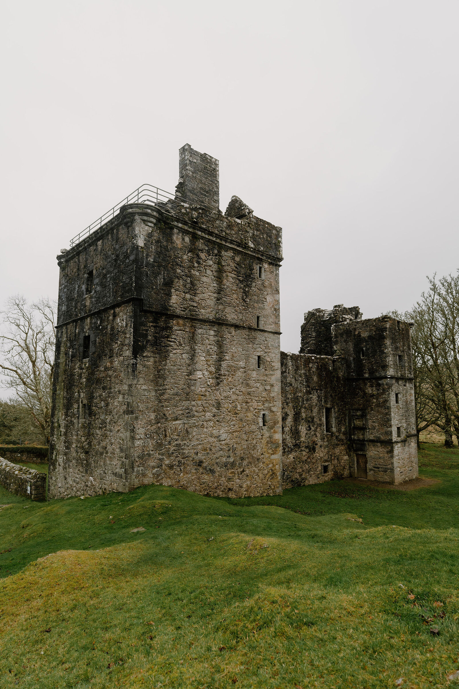 A ruined stone tower keep with a stepped gable, connected by a lower wing to a second tower