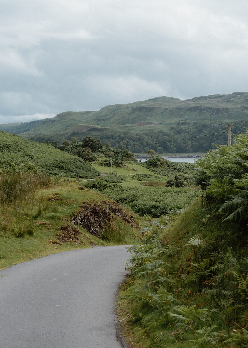 A road curving through green hills toward a sea loch near Oban.