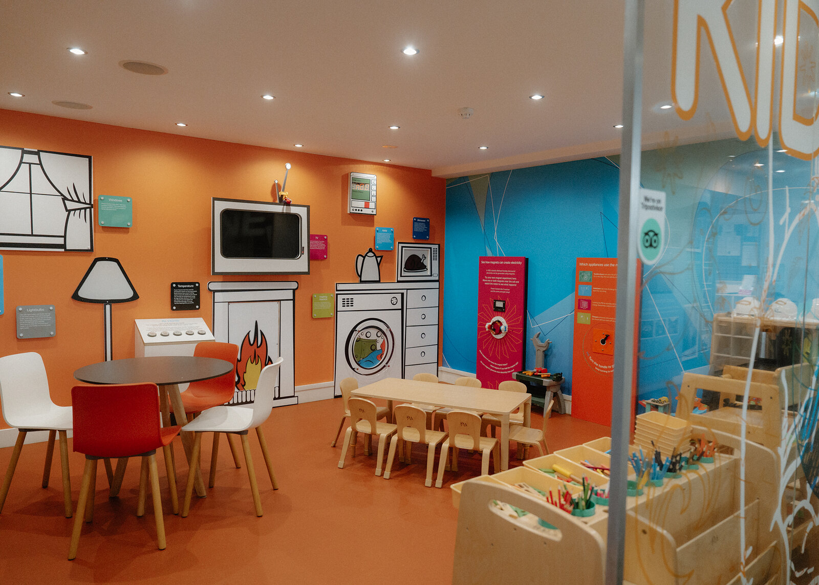 Painted appliance illustrations decorate a children's play corner with a play kitchen and craft table.