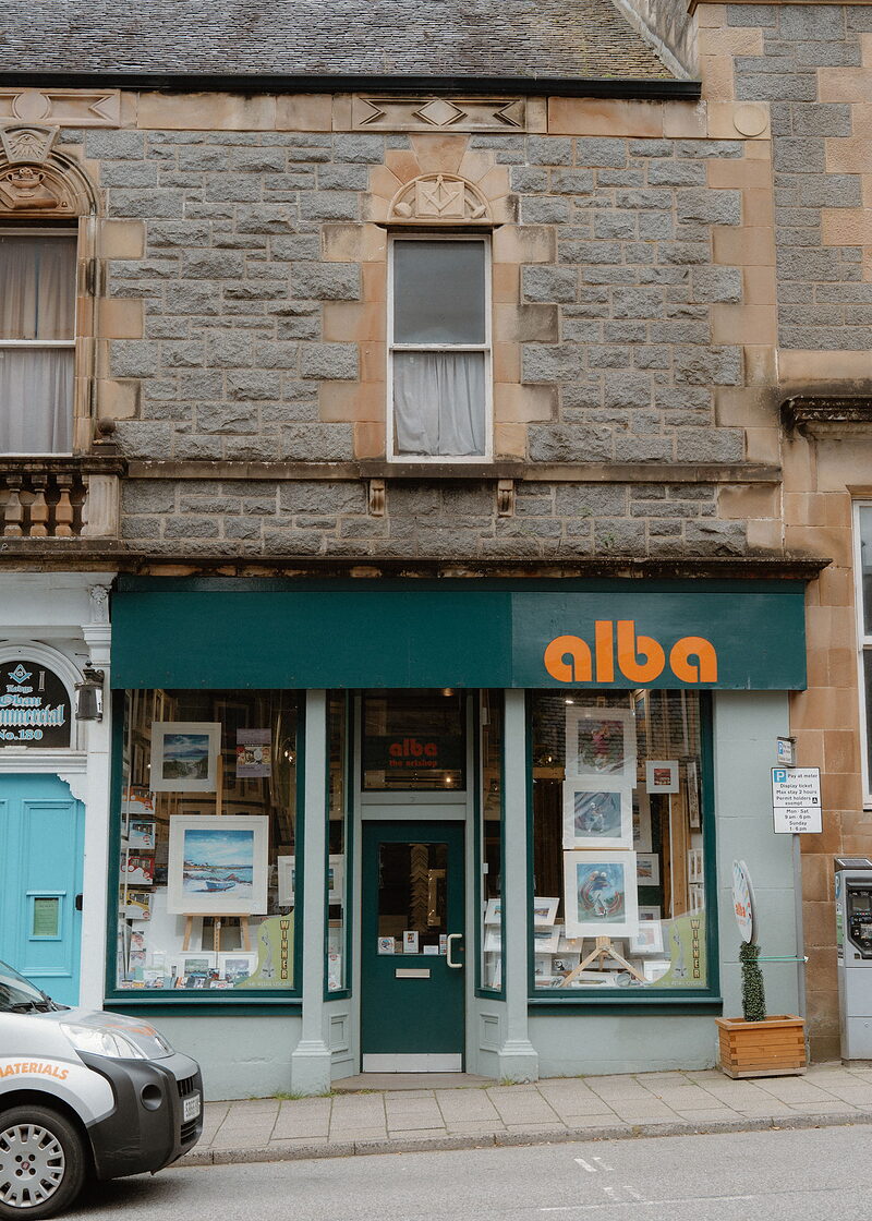 Alba's small teal shopfront with prints in the window, in a granite building with sandstone dressings.