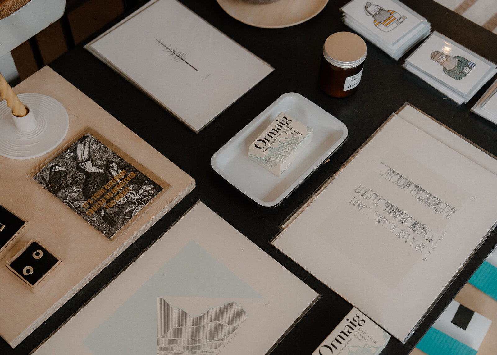 Prints, cards, earrings and Ormaig soap laid out on the shop's black and birch display table.