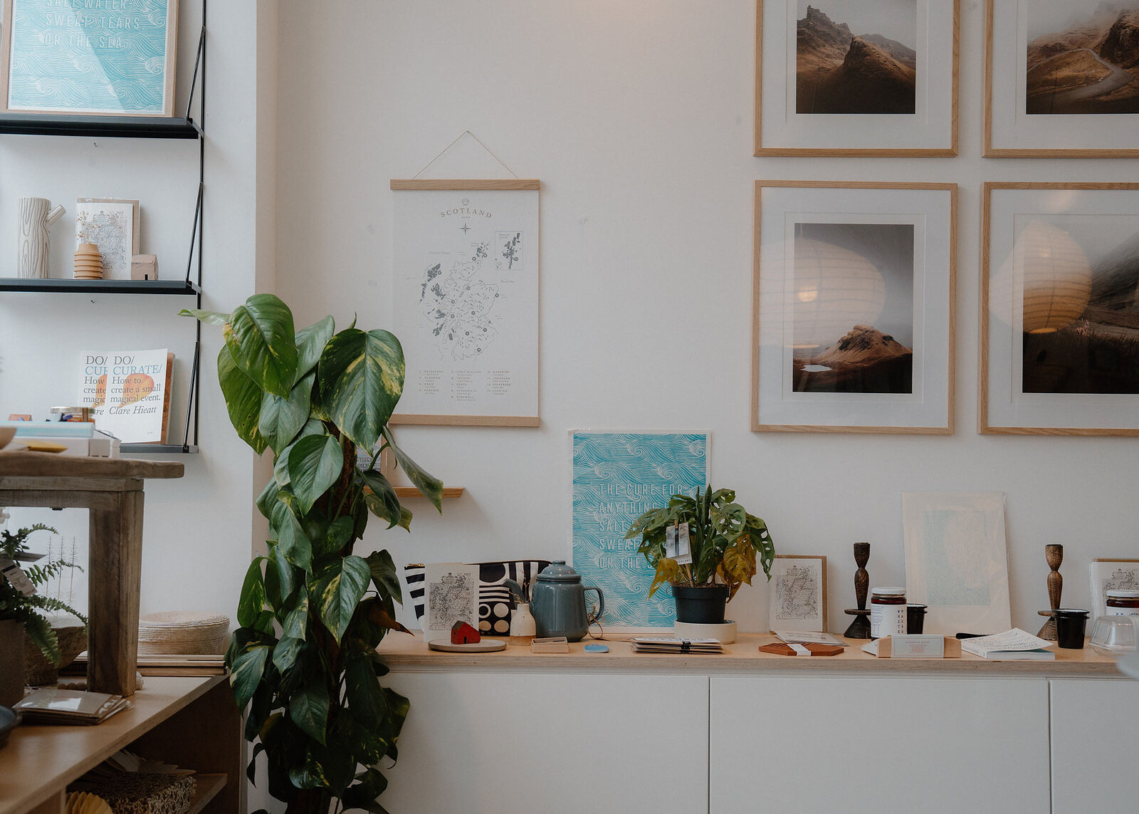 A landscape view of the shop's wall of framed mountain photographs and a map, homeware along the sideboard below.