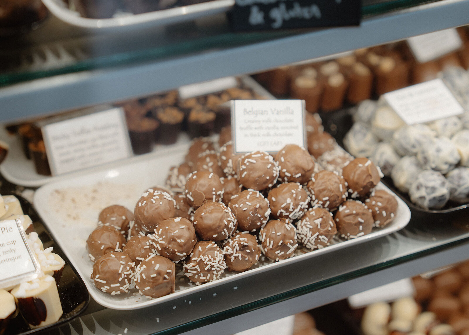 Trays of Belgian vanilla truffles rolled in sprinkles and other handmade chocolates in the cabinet.