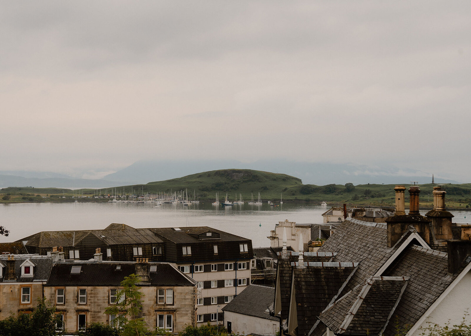 Over the town's roofs and chimneys to Oban Bay, the yachts moored off Kerrera and the hills of Mull in the haze.