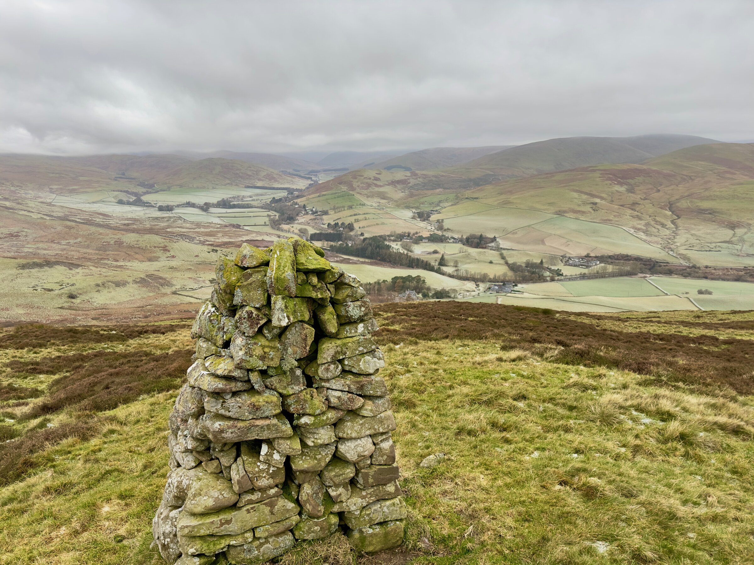 The cairn on the hill above Ladhope, a pillar of mossy stones, with the Yarrow Valley’s fields and hills spread out below.