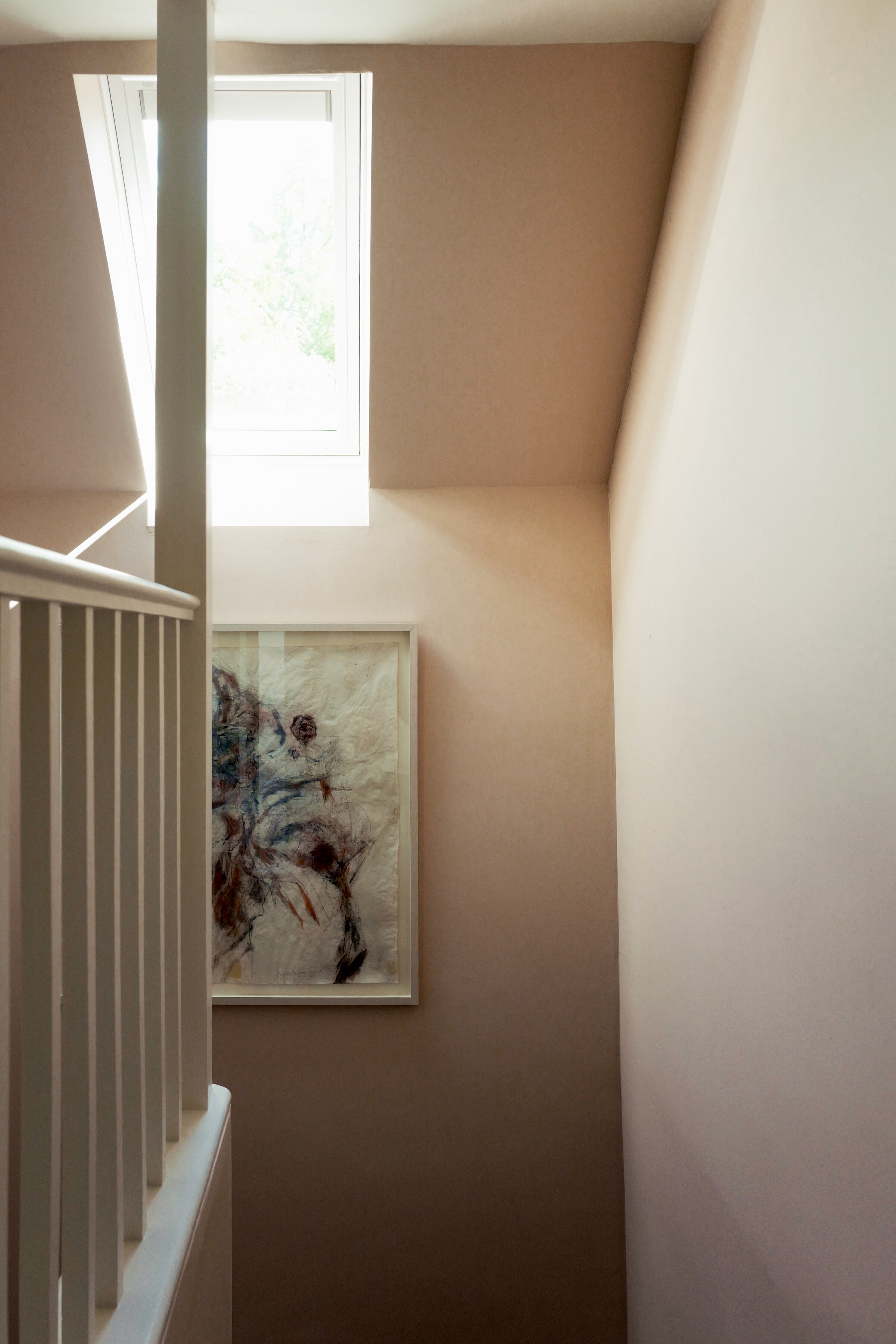 The pale stairwell lit from a high window, a single painting hung on the wall below it.
