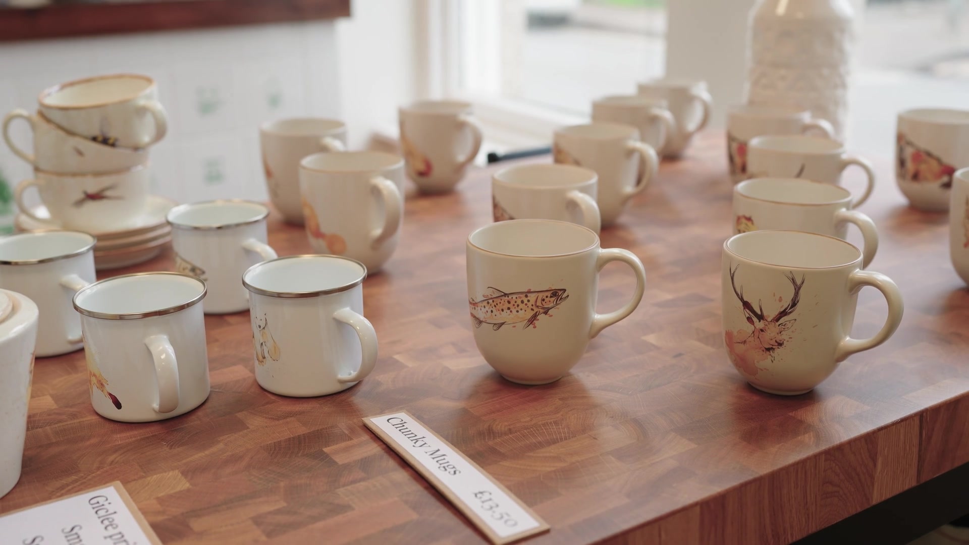 Rows of enamel mugs printed with foxes, polar bears and birds fill a gift shop table beneath a "Chunky Mugs" price sign.