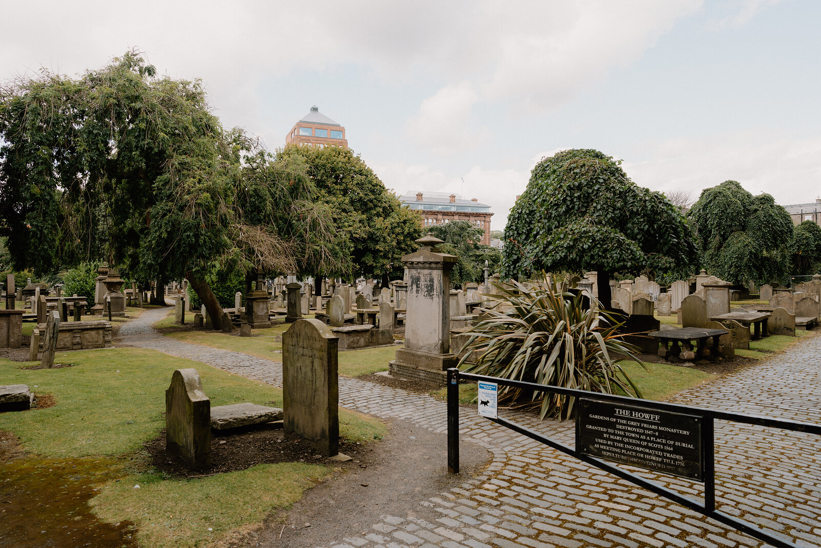 Old gravestones and table tombs among trees in the Howff, Dundee.