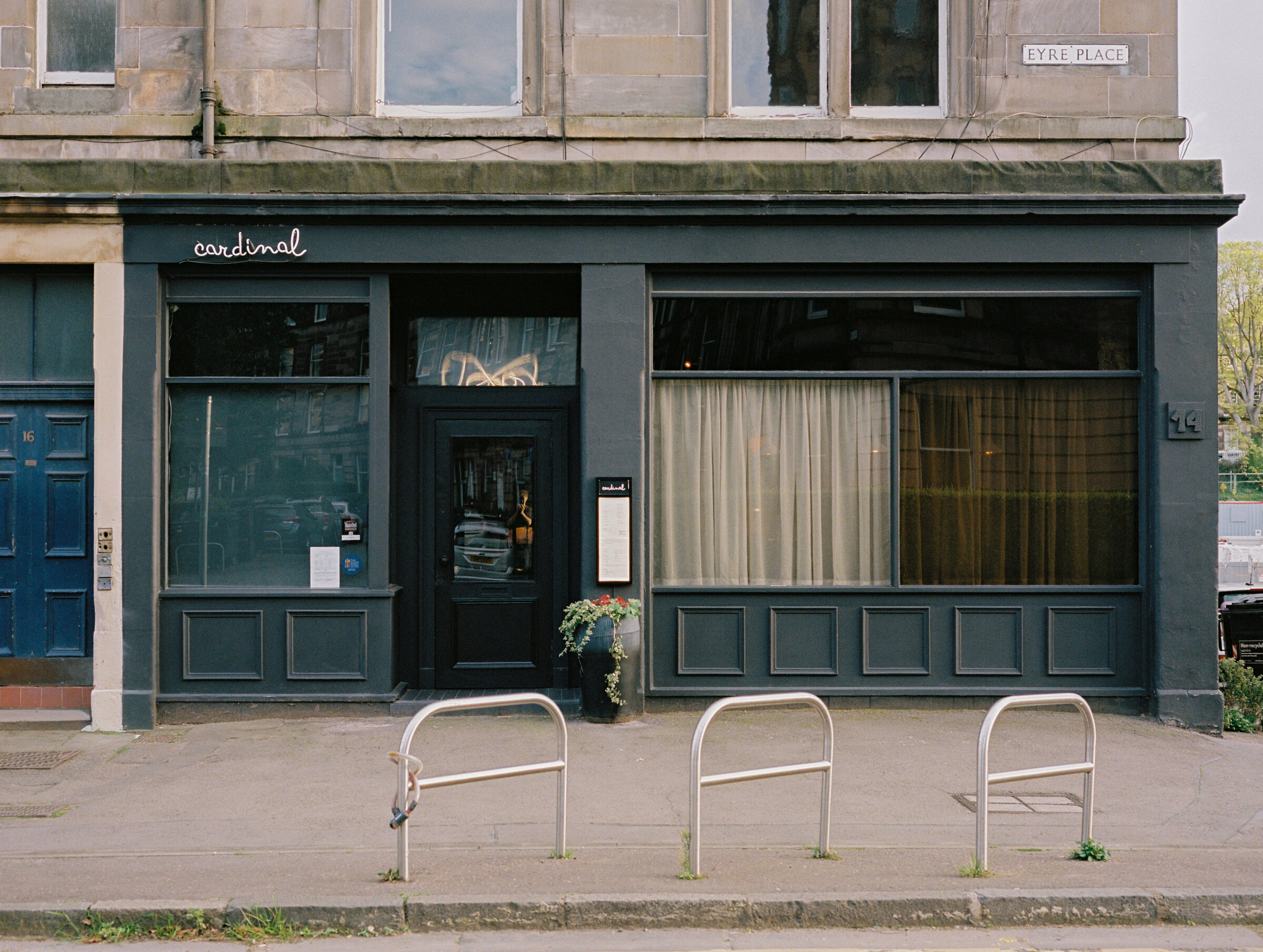 The front of Cardinal on Eyre Place, a dark green shopfront with its name in white script and bike racks on the pavement.