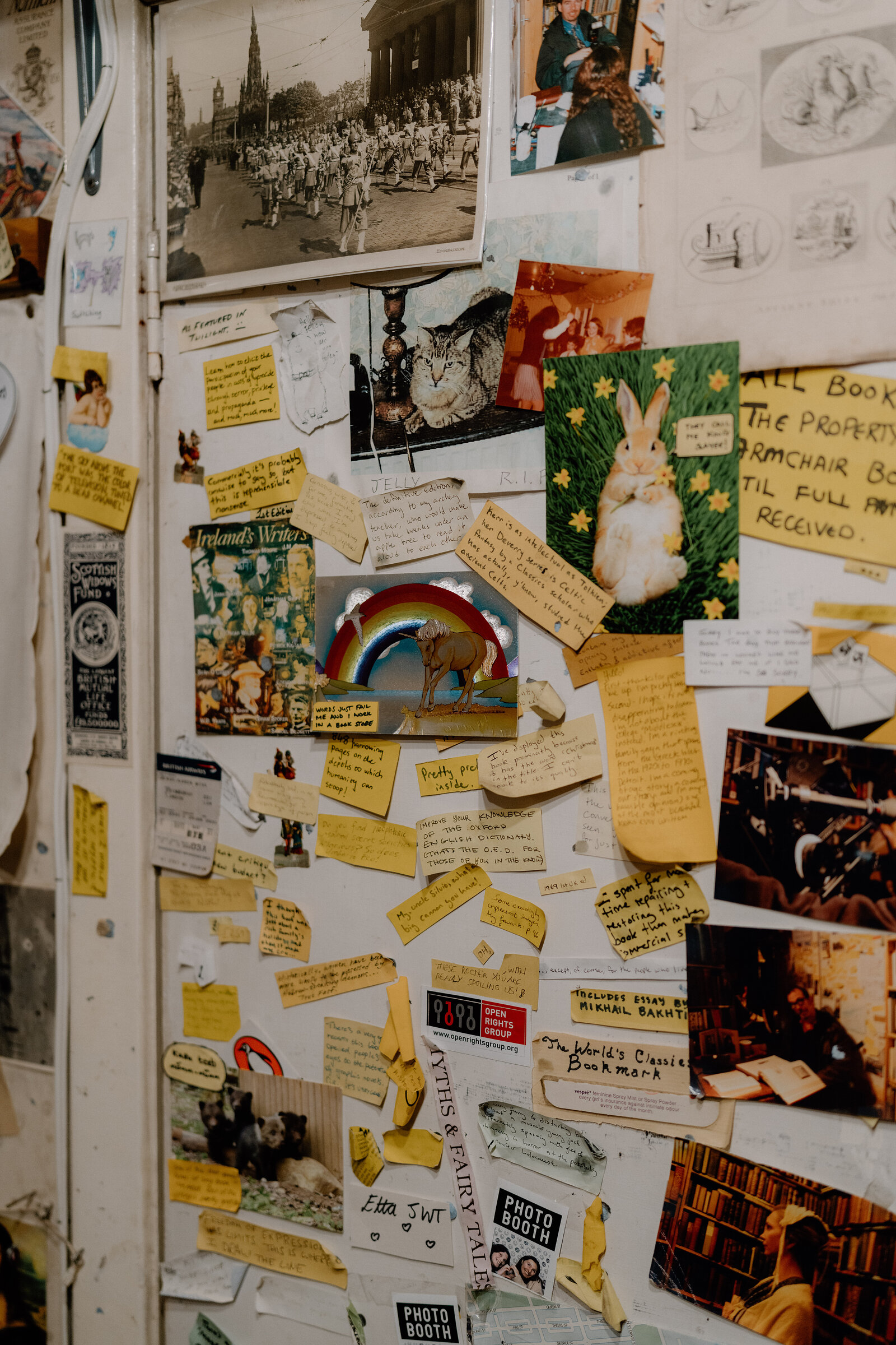 A cluttered notice board displays photographs, hand-written notes and a shop's ownership sign.