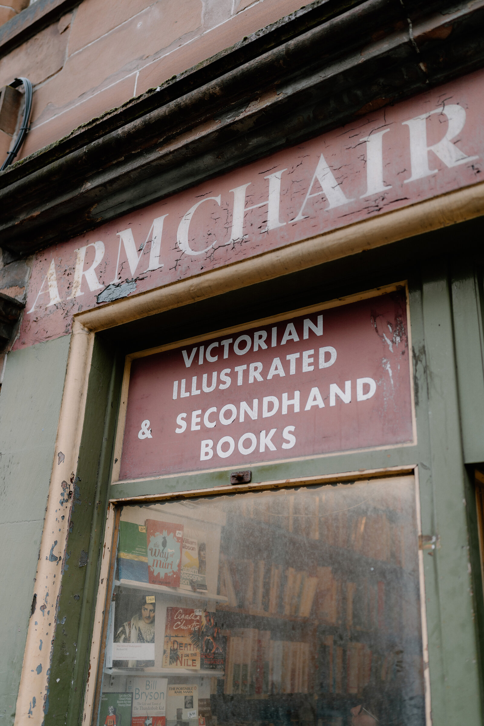 A weathered sign reads 'Armchair: Victorian Illustrated & Secondhand Books' above a shop window.