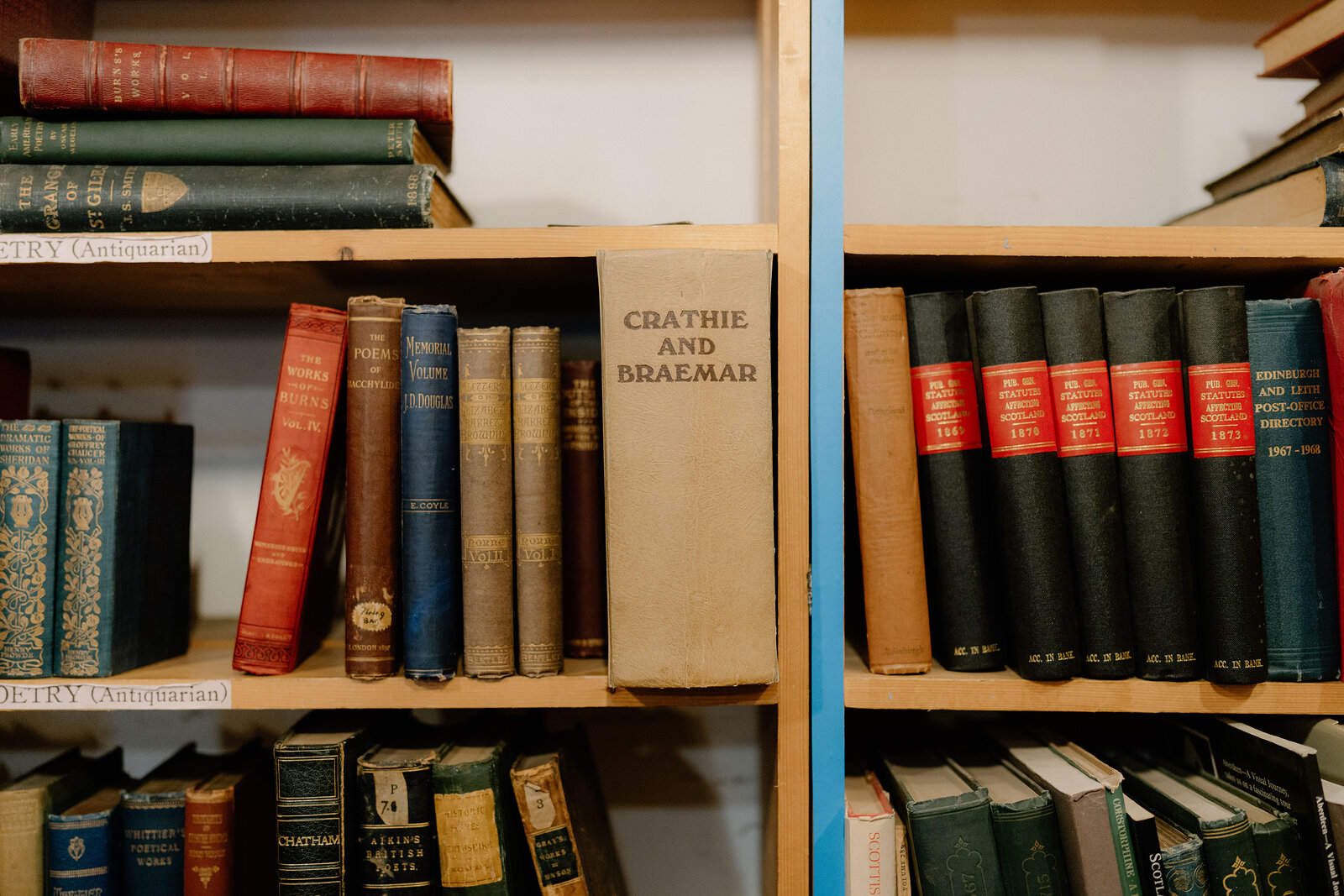 Leather-bound volumes including 'Crathie and Braemar' line an antiquarian bookshelf.