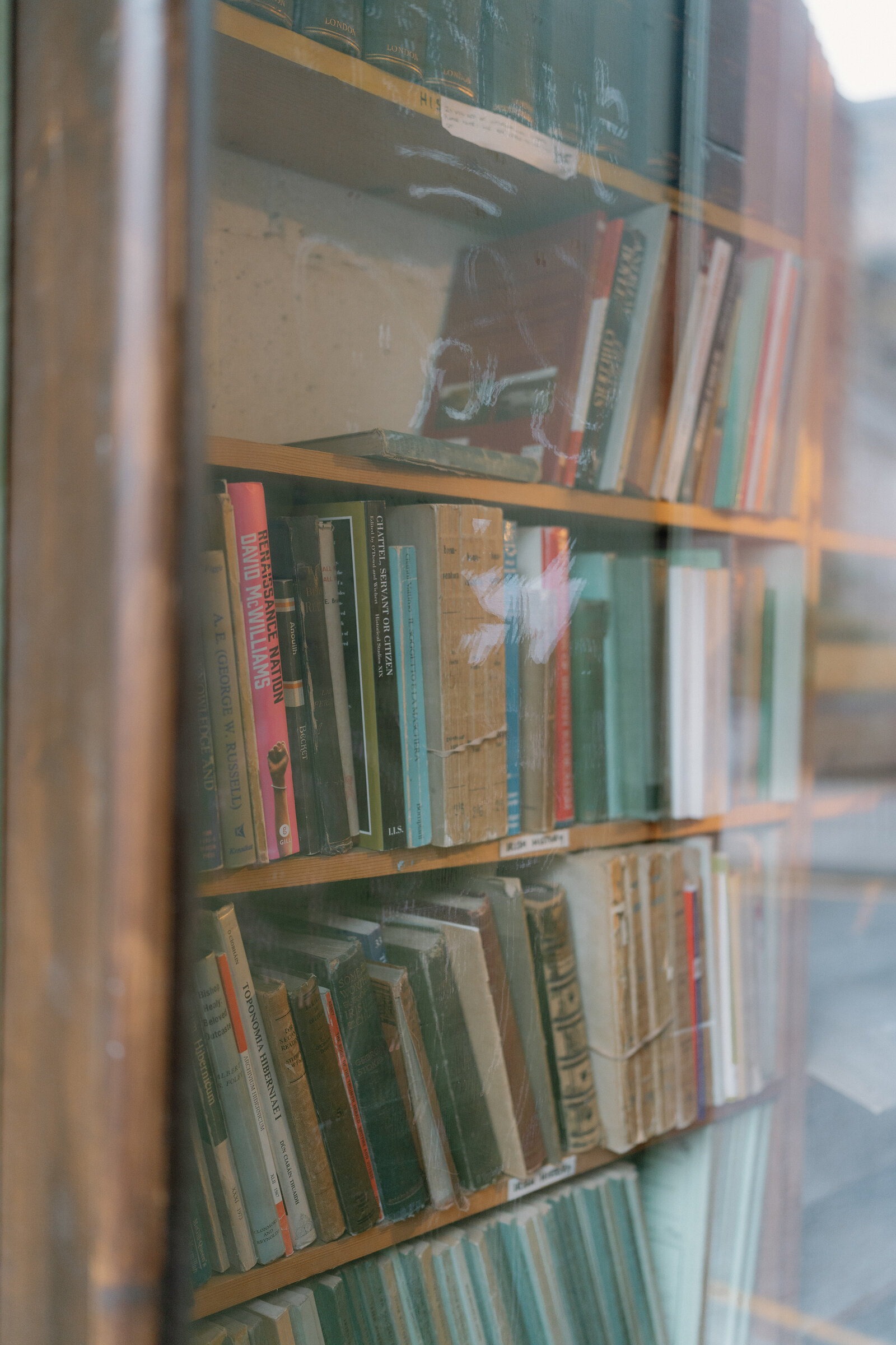 Antiquarian book spines crowd a shop window's glass shelves.
