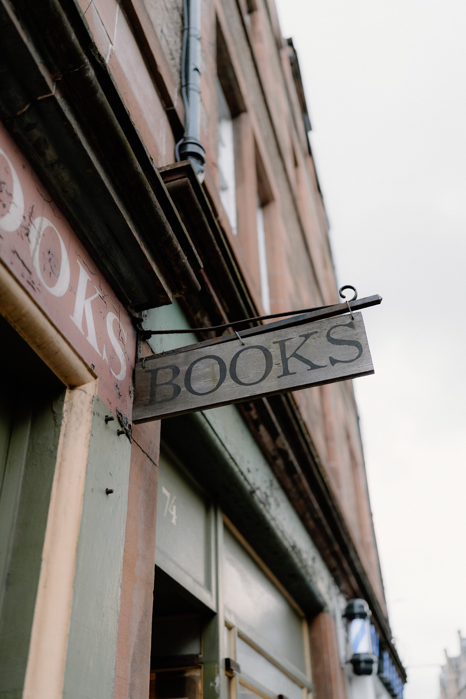 A weathered 'Books' sign hangs from a shopfront's cast-iron bracket.