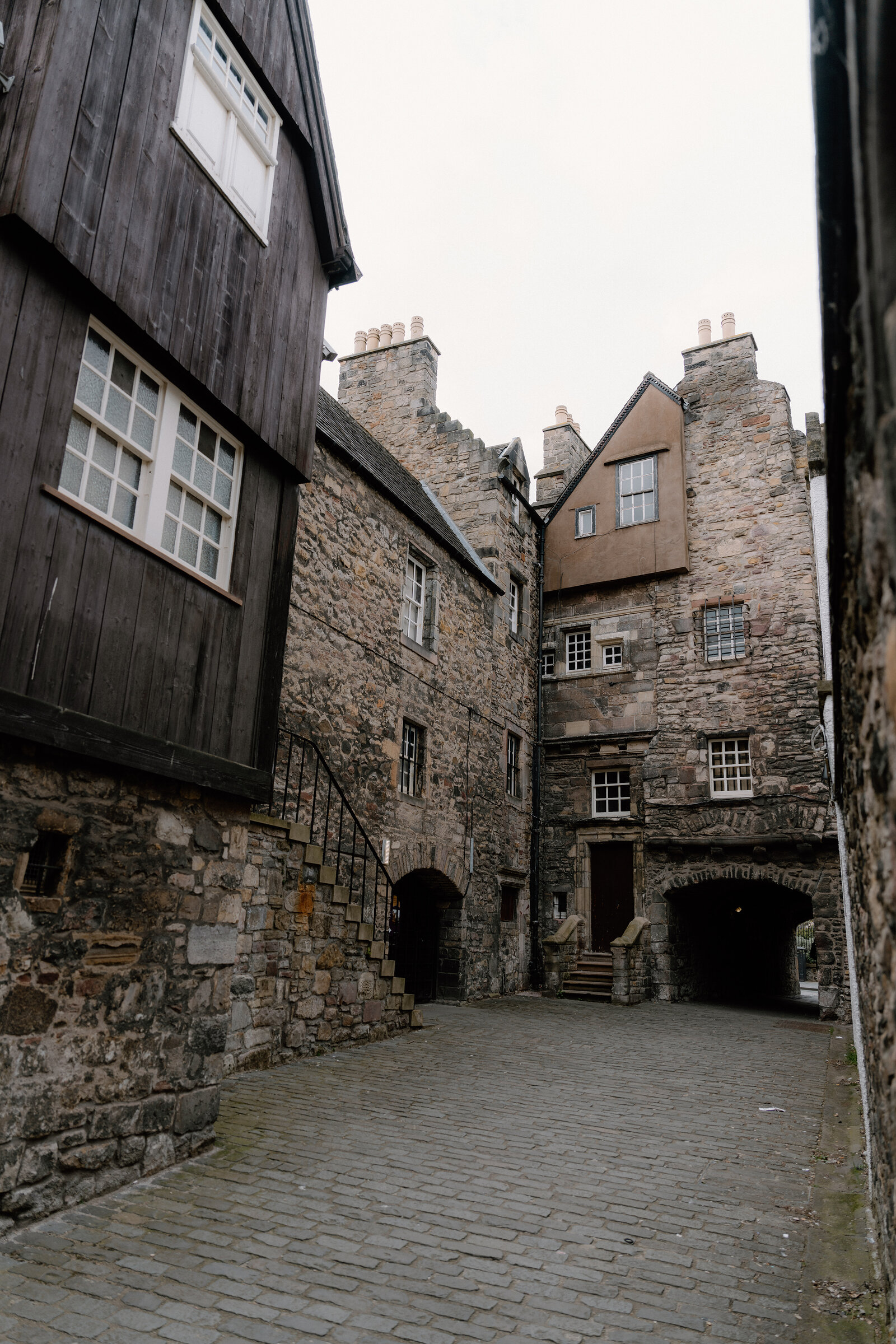 A cobbled courtyard in Edinburgh's Old Town, timber-fronted and stone buildings rising around an archway.