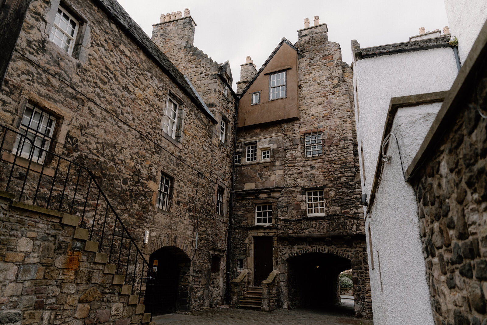 A cobbled Old Town courtyard in Edinburgh, timber and stone buildings rising around an archway passage.