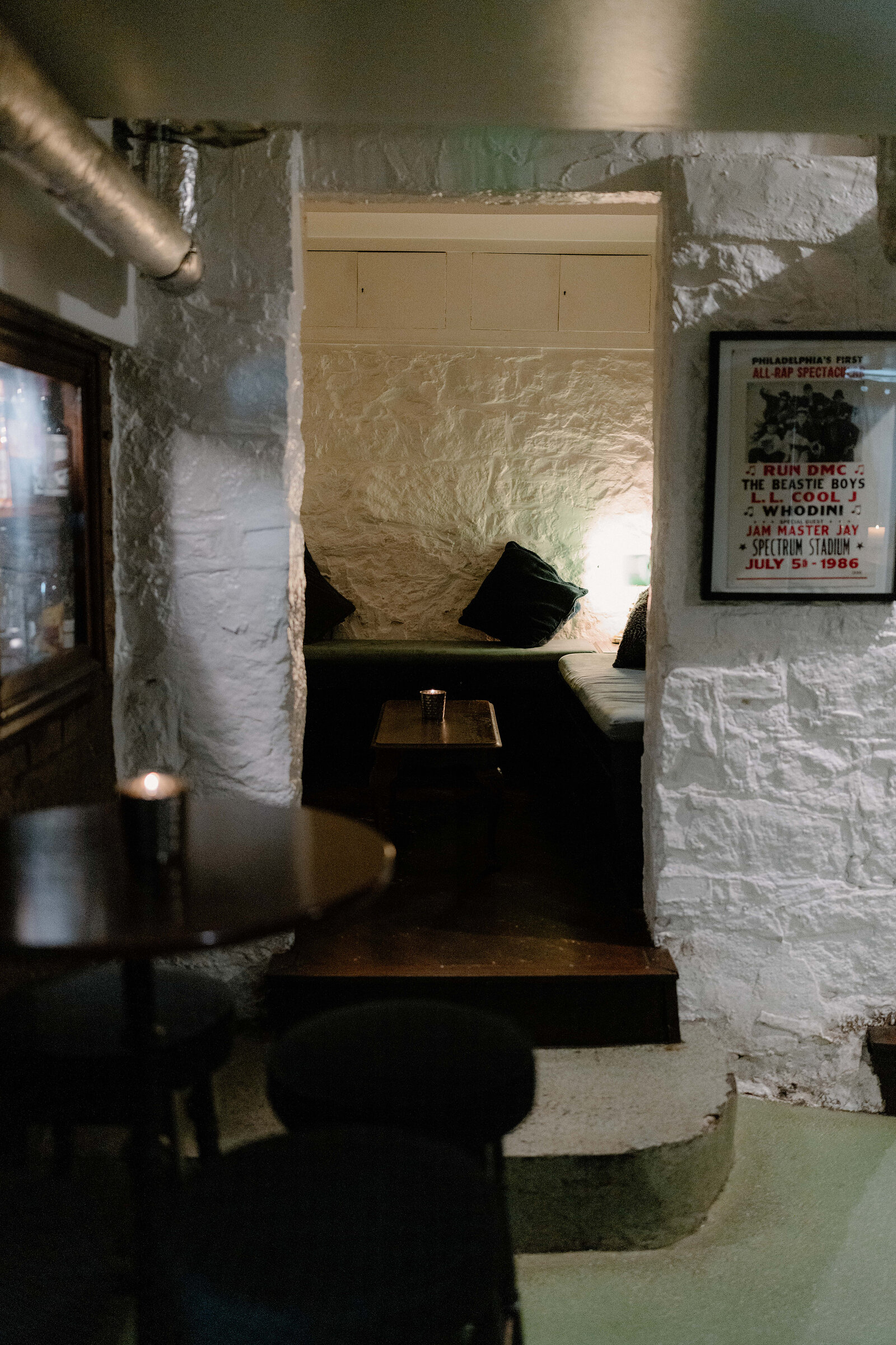 A cosy underground seating nook in Edinburgh, a framed concert poster hanging on the stone wall.