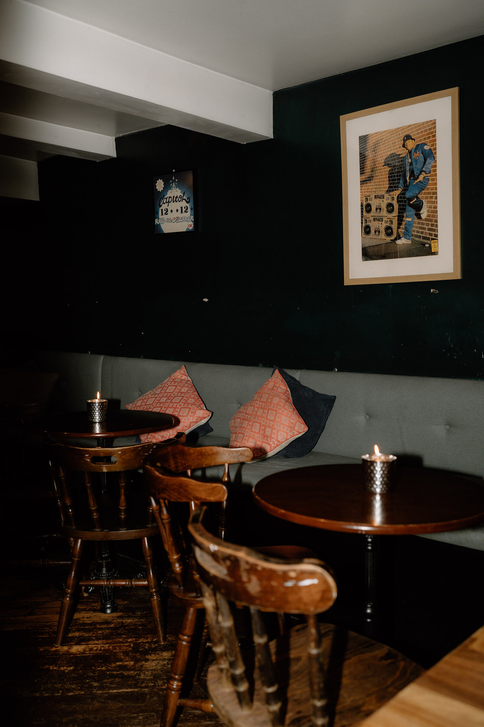 A booth seating area with pink cushions and a framed illustration of a saxophonist on the wall.
