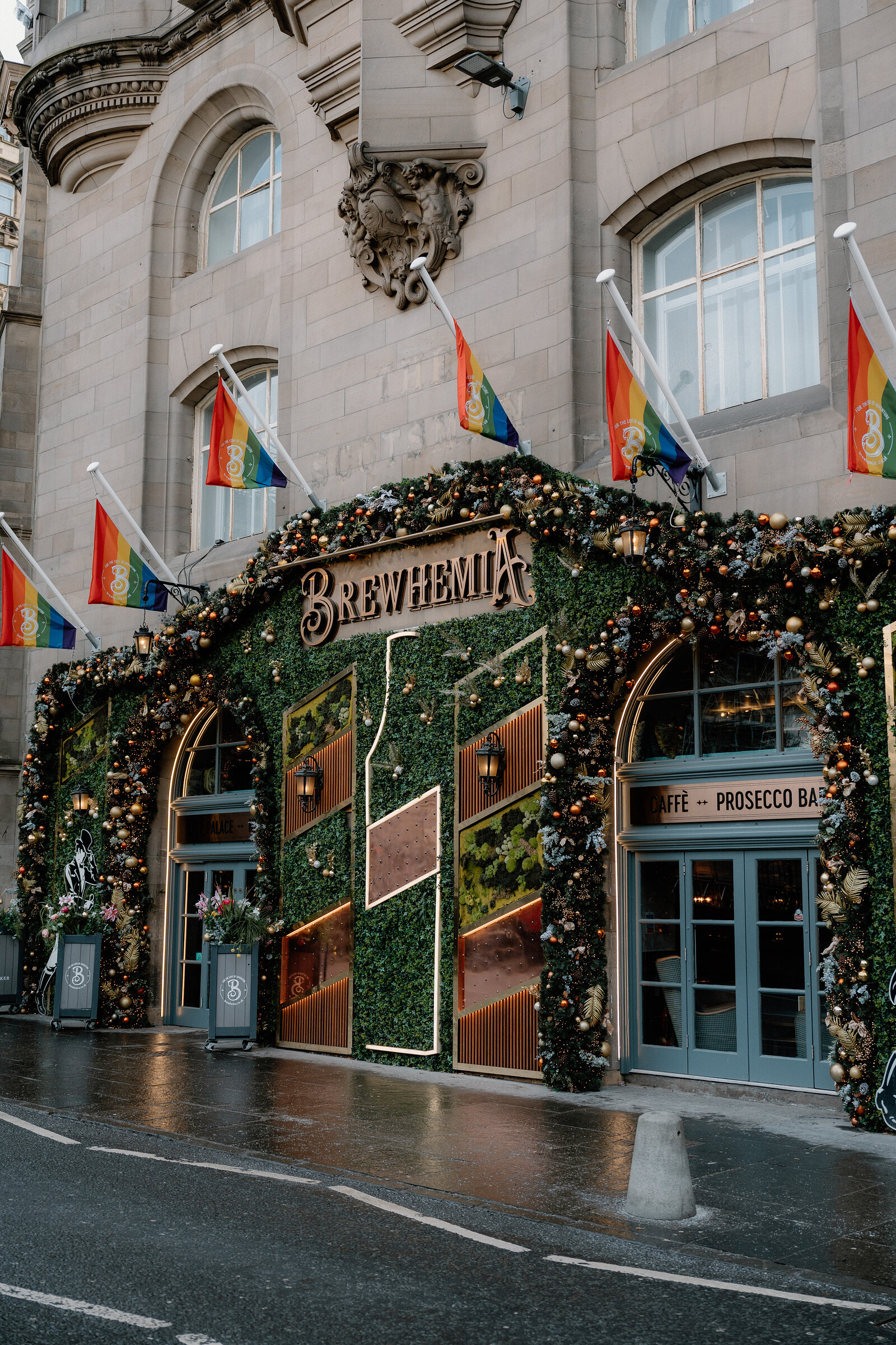 Brewhemia's own sign above a hedge-covered entrance strung with festive lights and rainbow flags.