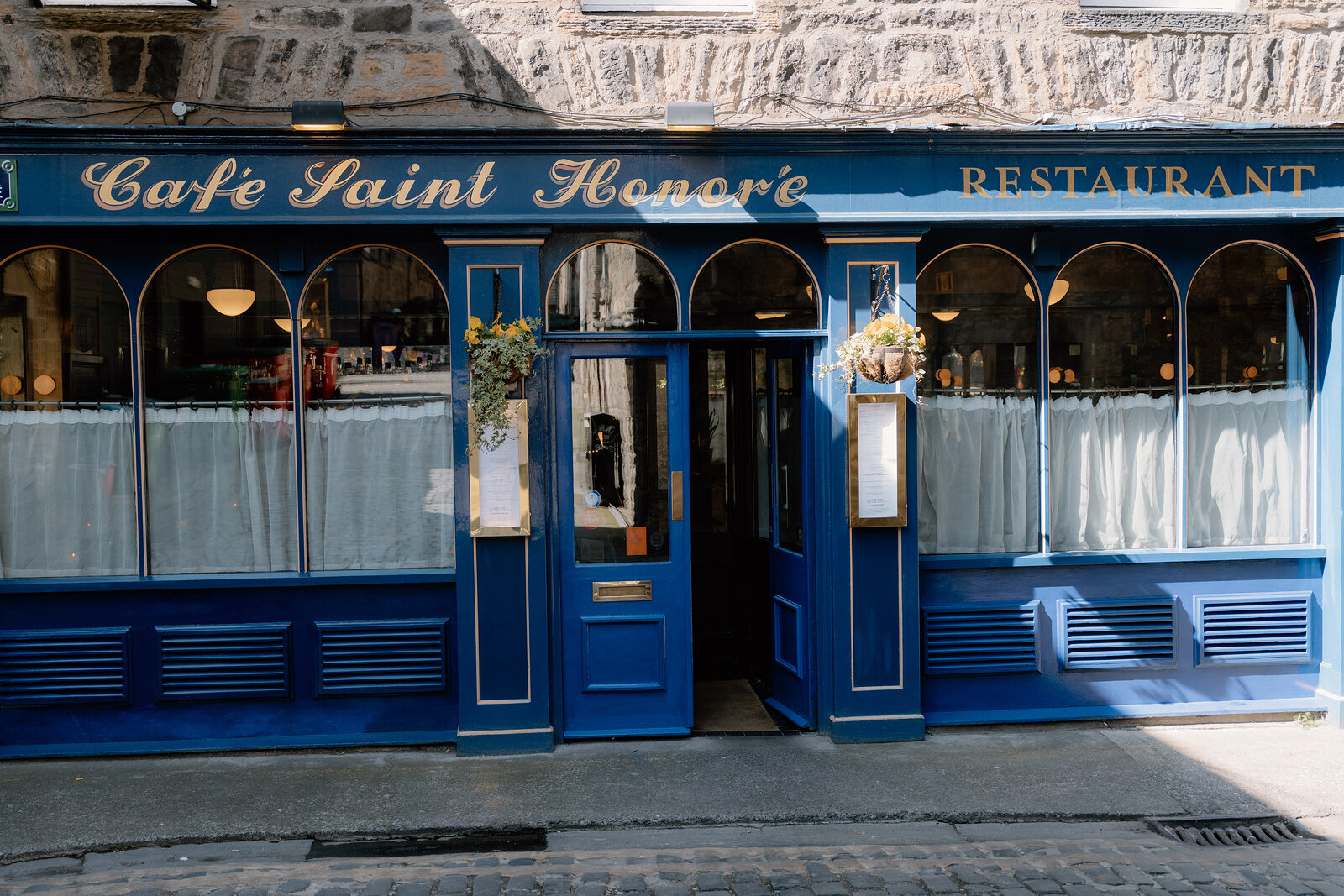 Café Saint Honoré's own gold lettering runs across its blue-painted restaurant frontage.