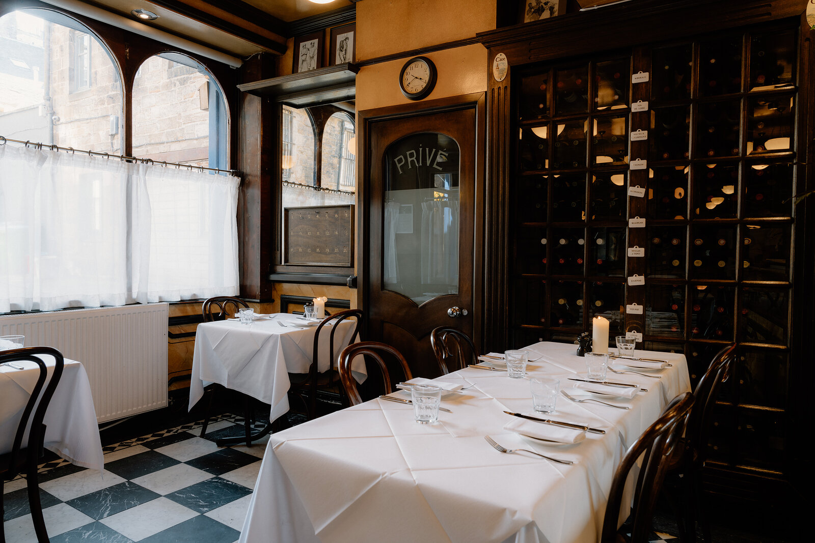 A door marked Prive stands beside floor-to-ceiling wine racks in a restaurant's dining corner.
