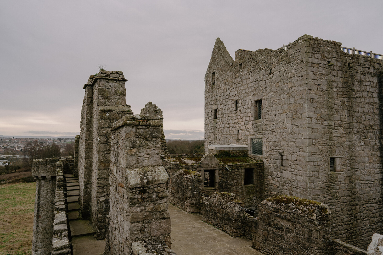 A cobbled path leads through a ruined castle courtyard toward its tower keep.