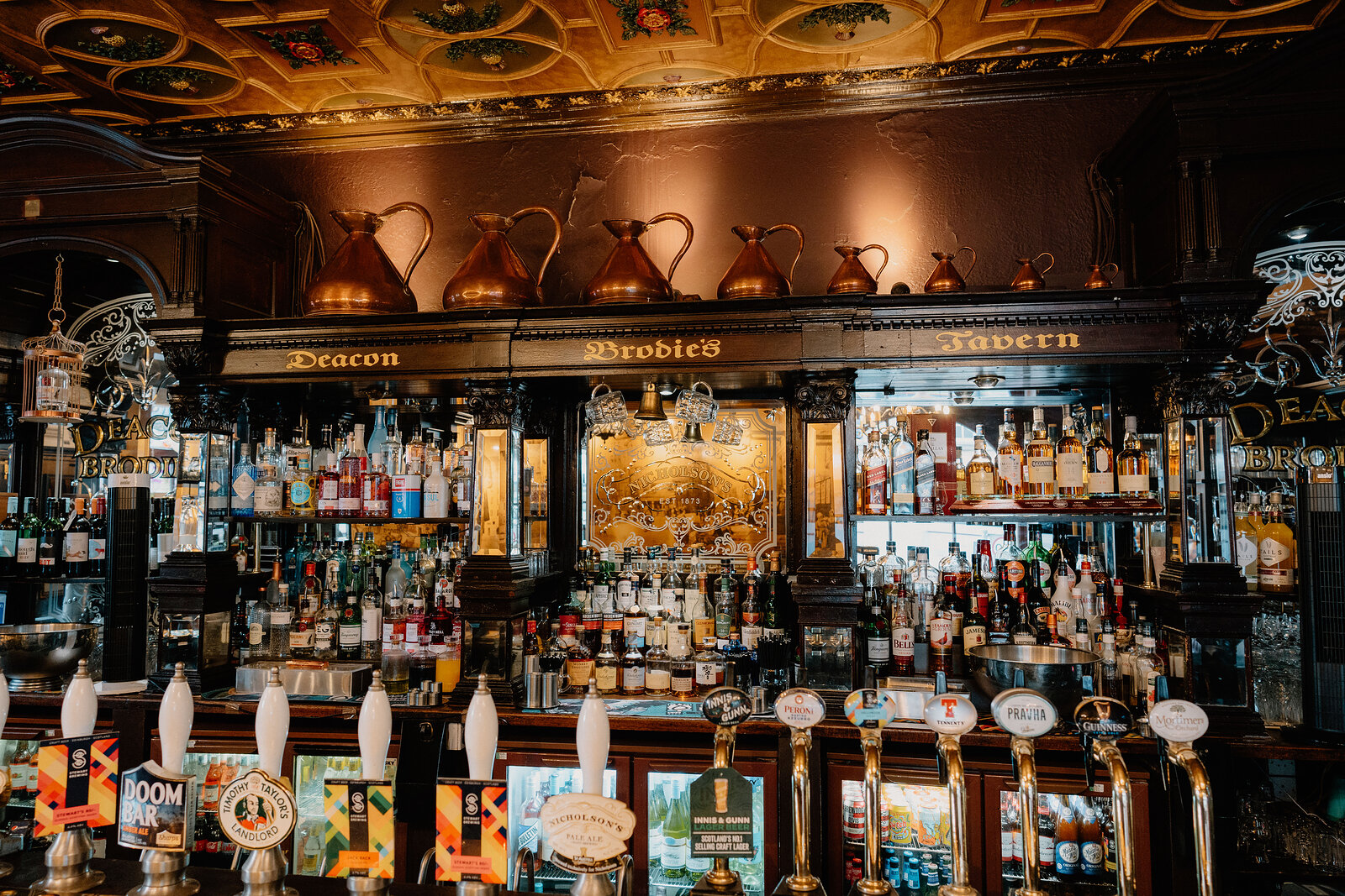 An ornate painted ceiling arches above the bar at Deacon Brodie's Tavern.