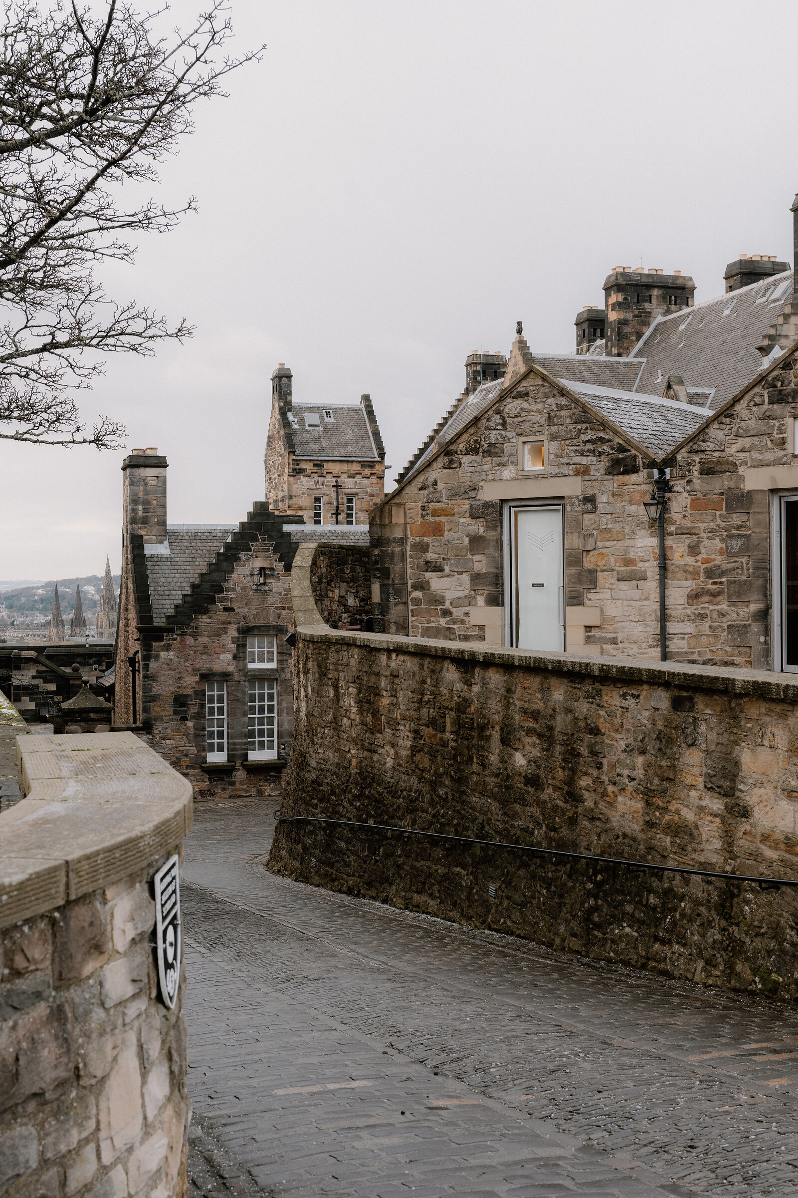 Crow-stepped stone buildings line a cobbled path within Edinburgh Castle's walls.