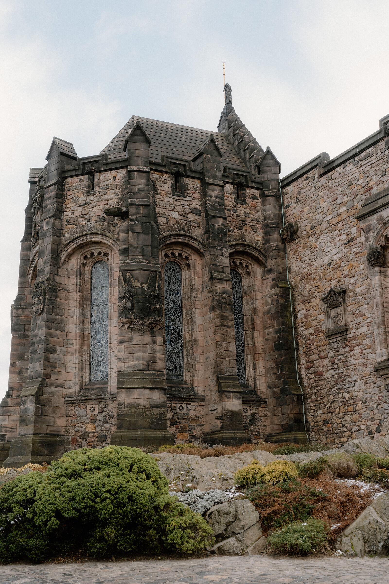 Carved gothic windows and a spire crown a stone tower within Edinburgh Castle's walls.