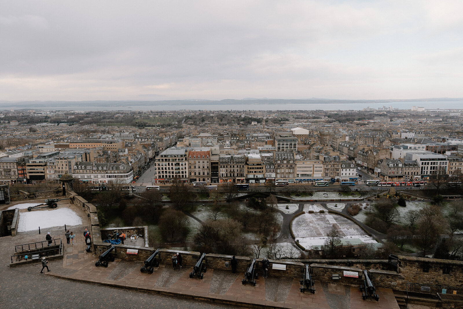 Snow dusts Edinburgh's rooftops and the row of cannon along the castle esplanade, the city spread out below.