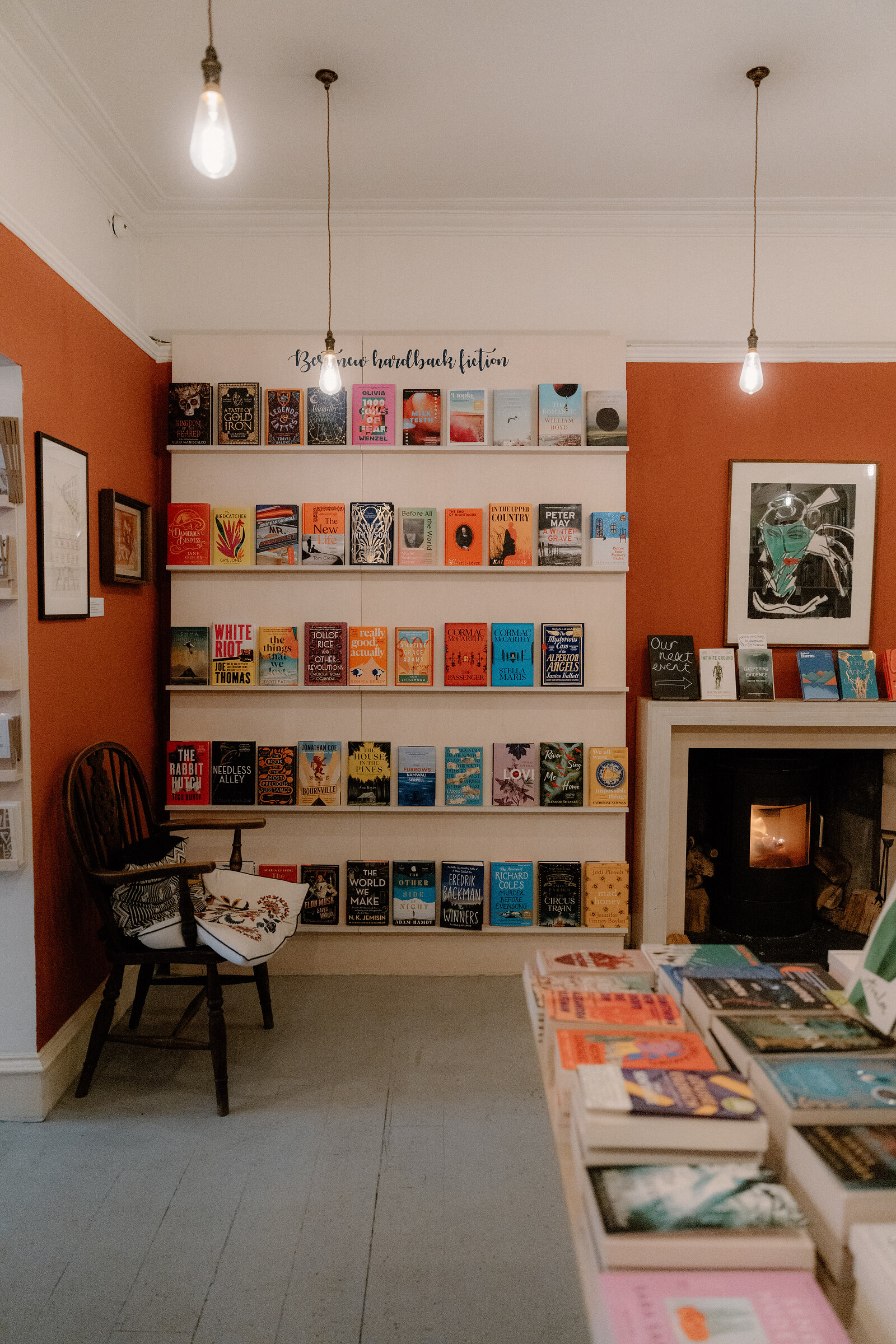 Orange walls hold shelves of paperbacks beside a lit stove at Golden Hare Books.
